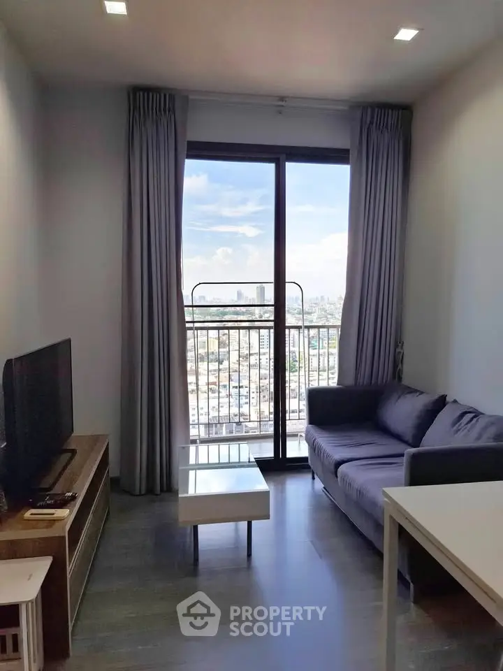 Modern living room with city view, featuring a cozy sofa and sleek TV setup, perfect for urban living.