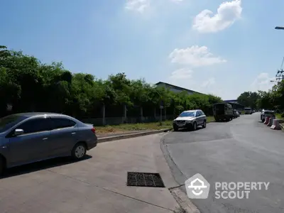 Spacious road view with lush greenery and clear blue sky, ideal for real estate development.