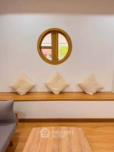 Charming living room with round window and cozy seating area, perfect for relaxation.