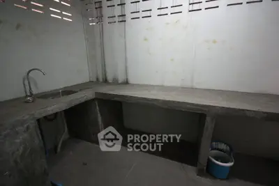 Minimalist concrete kitchen with open shelving and single sink