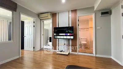Modern living room with TV, wooden flooring, and adjacent bathroom in a stylish apartment.