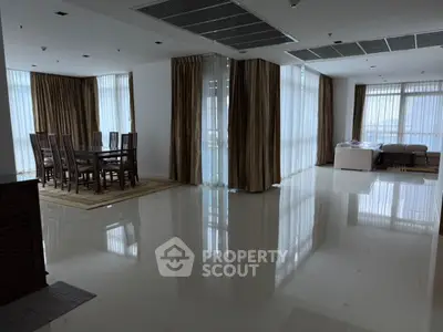 Spacious open-plan living and dining area with large windows and elegant curtains.