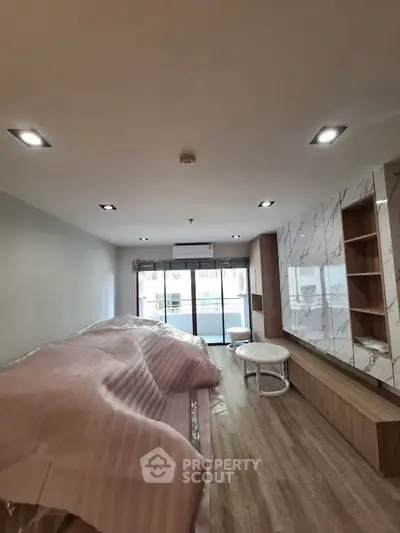 Modern living room with stylish wood flooring and marble accents, featuring large windows for natural light.