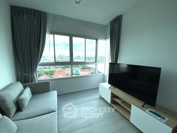 Modern living room with large window and city view, featuring sleek furniture and natural light.