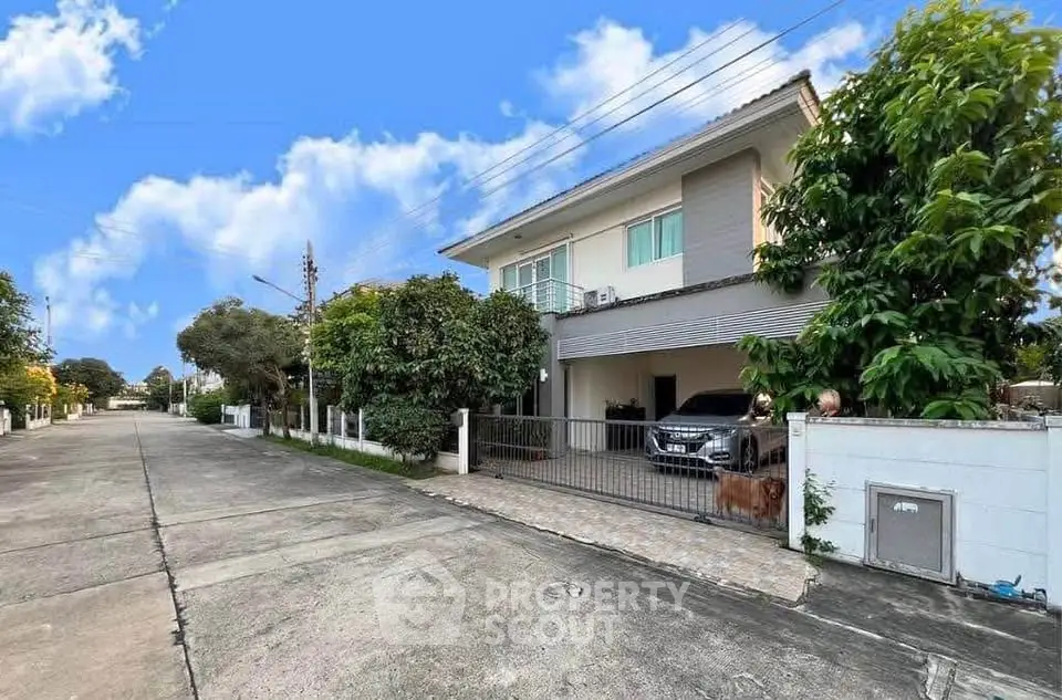 Charming suburban house with spacious driveway and lush greenery under a clear blue sky.