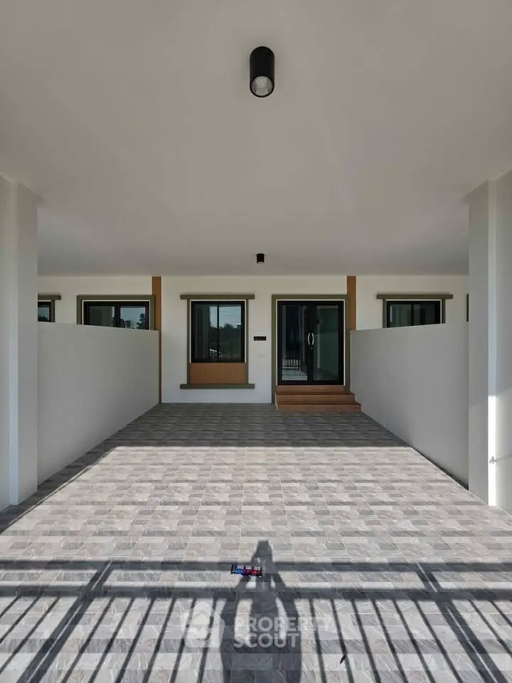 Modern house entrance with spacious tiled driveway and sleek design
