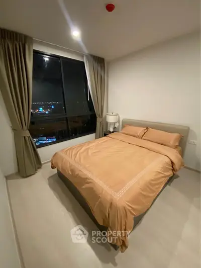 Cozy bedroom with city view, featuring a comfortable bed and elegant curtains.