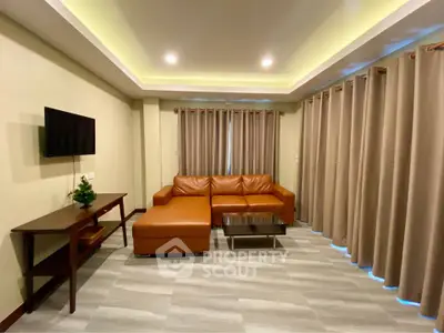 Spacious living room with modern leather sofa and wall-mounted TV, perfect for relaxation.