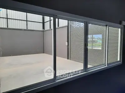 Spacious industrial storage unit with large window and high ceilings.