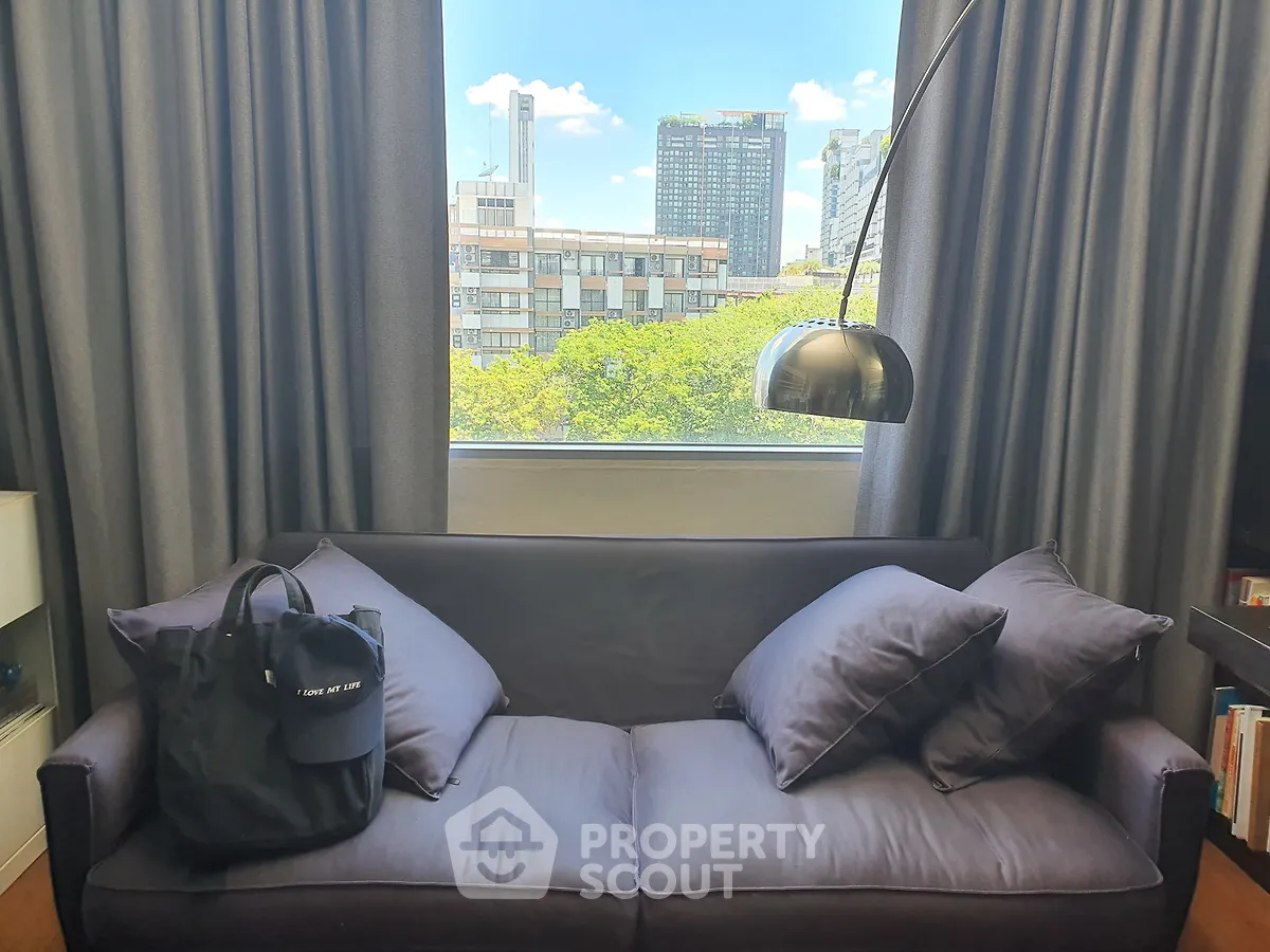 Stylish living room with modern sofa and city view through large window, perfect for urban living.