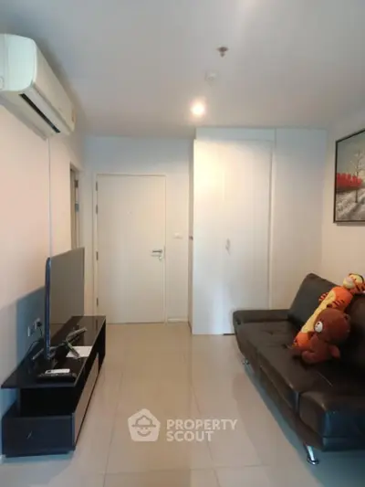 Modern living room with sleek black sofa and wall-mounted TV, perfect for cozy relaxation.