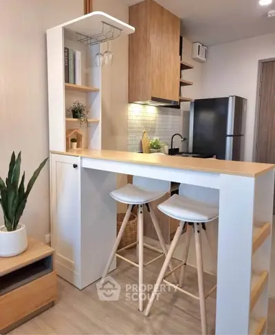 Modern kitchen with sleek bar counter and stylish stools, featuring a compact design and contemporary decor.