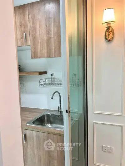 Compact kitchen with wooden cabinets and modern lighting