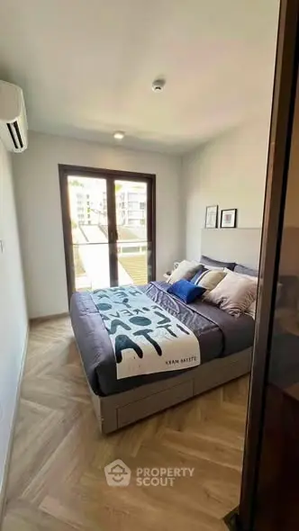 Modern bedroom with stylish decor and large window offering natural light.