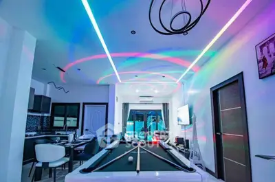 Modern living room with pool table and vibrant LED lighting, open kitchen layout, stylish decor.