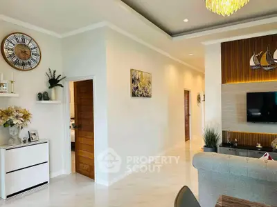 Elegant living room with modern decor and wall-mounted TV, featuring stylish lighting and wooden accents.