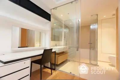 Sleek modern bathroom with glass shower enclosure and spacious vanity area, featuring warm lighting and a clean design.