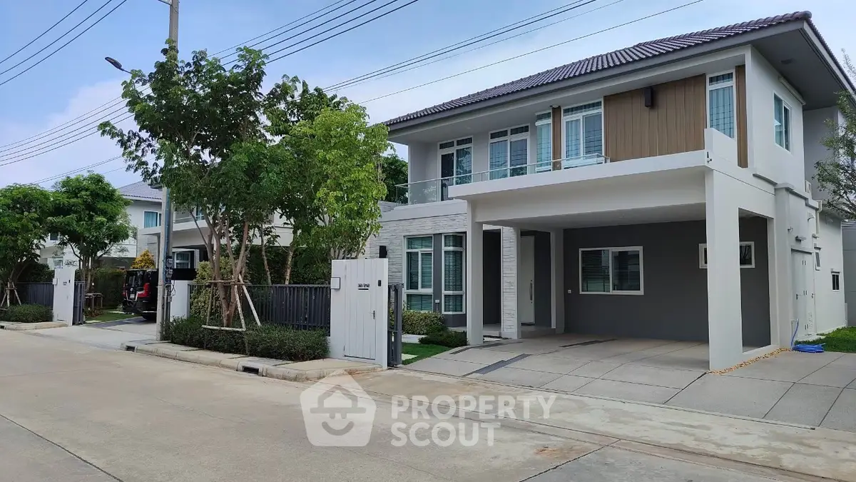 Modern two-story house with spacious driveway and lush greenery in a serene neighborhood.
