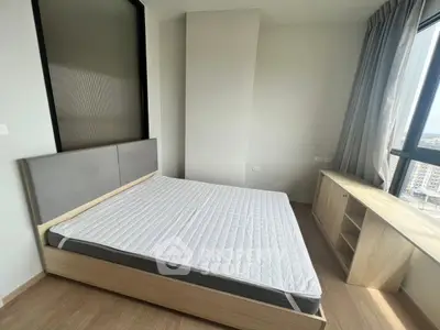 Modern bedroom with large window and minimalist furniture in a high-rise apartment.