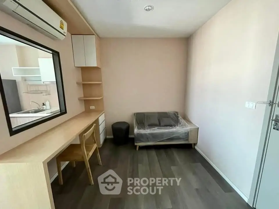 Modern study room with desk, chair, and sofa in a minimalist apartment setting.