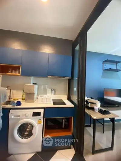 Modern kitchen with blue cabinets and built-in washing machine in open layout