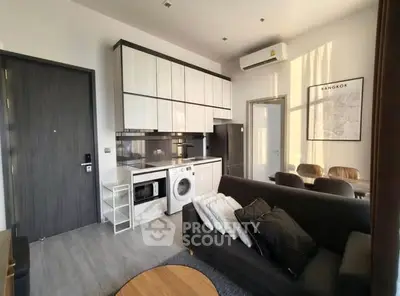 Modern living room with integrated kitchen and washing machine in Bangkok apartment.