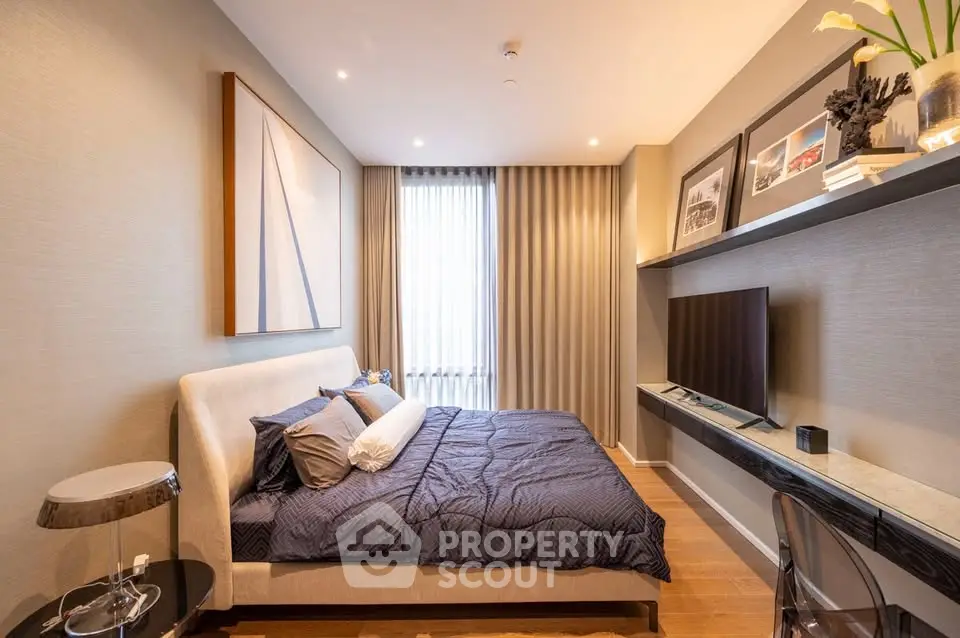 Modern bedroom with stylish decor, large bed, and wall-mounted TV in a cozy apartment setting.