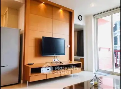 Modern living room with sleek TV unit and large glass doors leading to balcony.