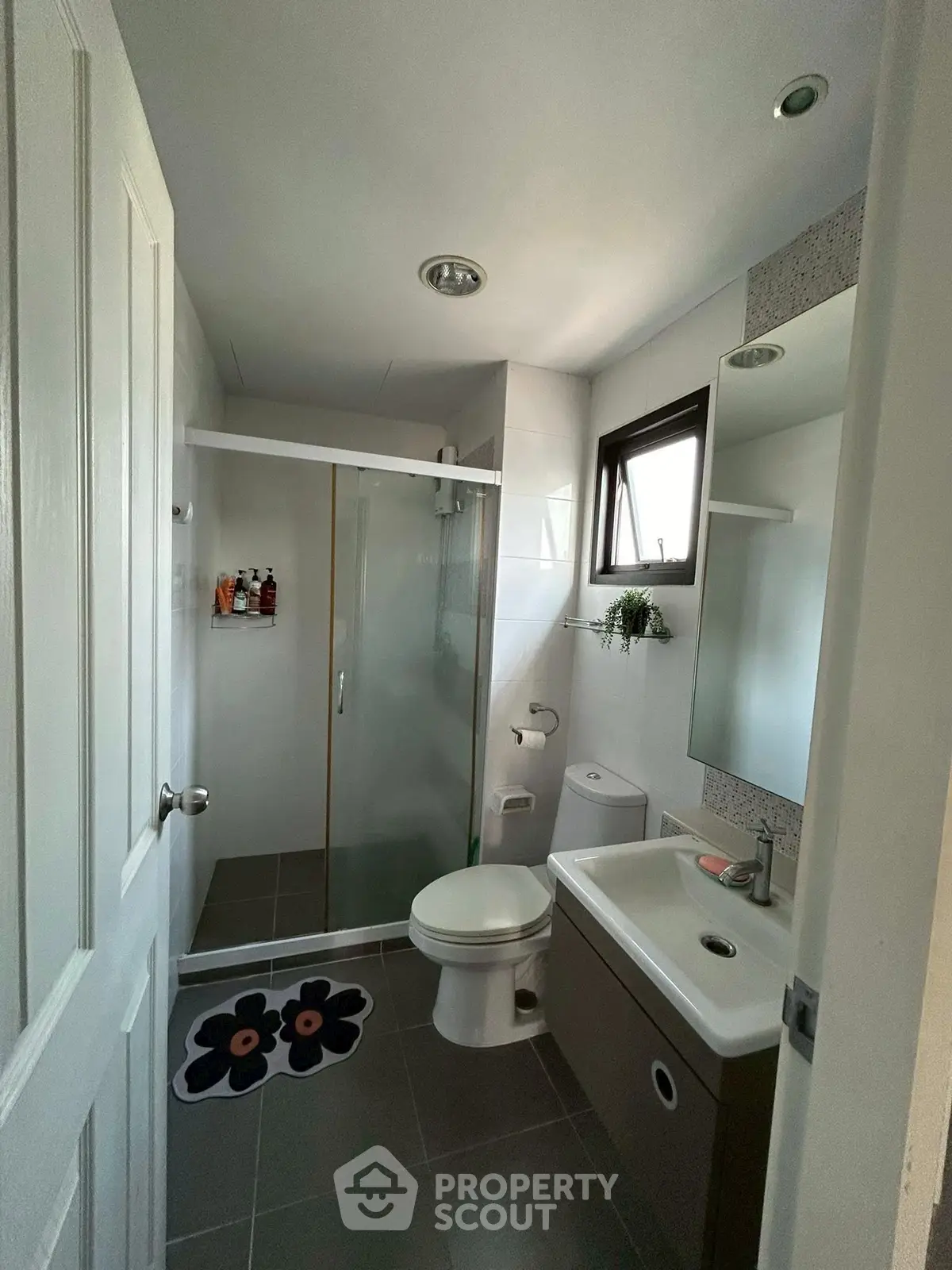 Modern bathroom with glass shower and sleek fixtures in a compact layout.