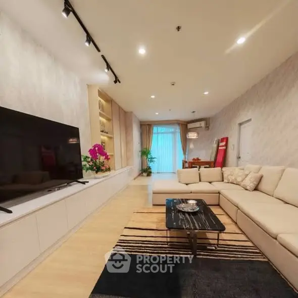 Spacious modern living room with elegant decor and large TV, perfect for relaxation and entertainment.
