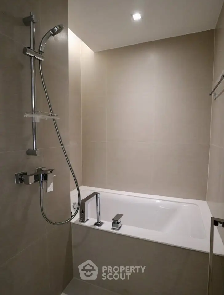 Modern bathroom with sleek bathtub and shower in elegant neutral tones.