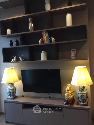 Elegant living room with custom shelving, chic decor, and ambient lighting from stylish table lamps flanking a modern flat-screen TV.