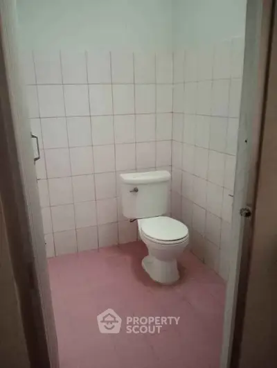Compact bathroom with tiled walls and floor featuring a standard toilet.