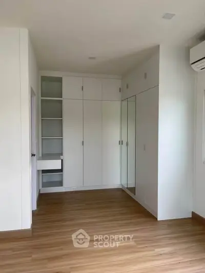 Spacious bedroom with built-in wardrobe and wooden flooring in modern apartment.