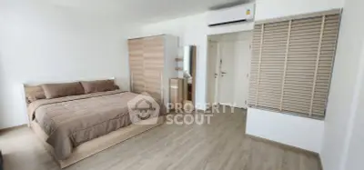 Spacious modern bedroom with wooden flooring and minimalist decor
