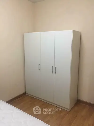 Minimalist bedroom with white wardrobe and wooden flooring