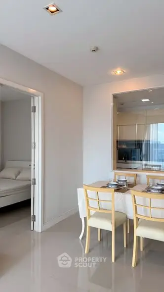Modern dining area with elegant table setting and view into a cozy bedroom.
