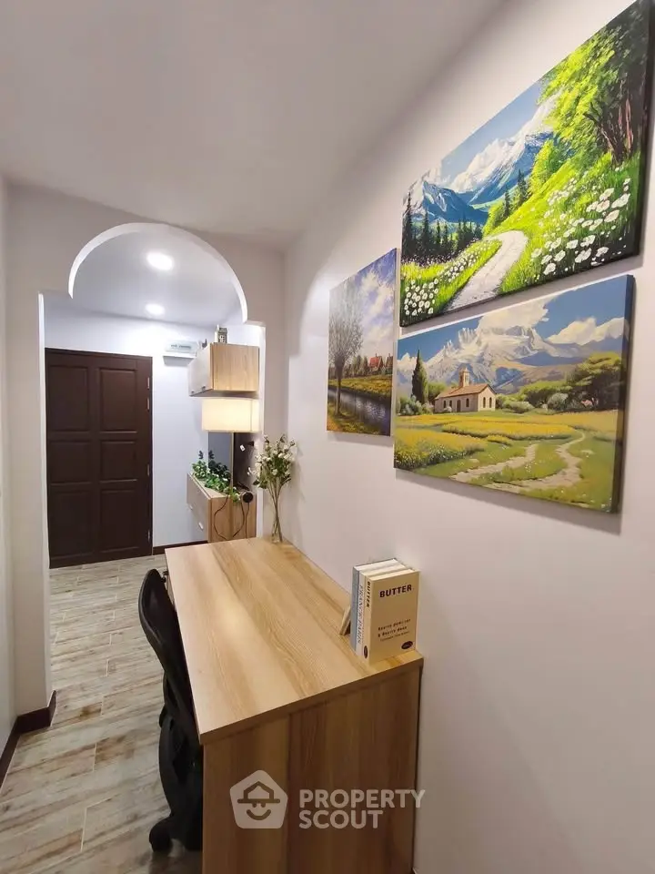 Charming study nook with scenic artwork and wooden desk in cozy hallway.