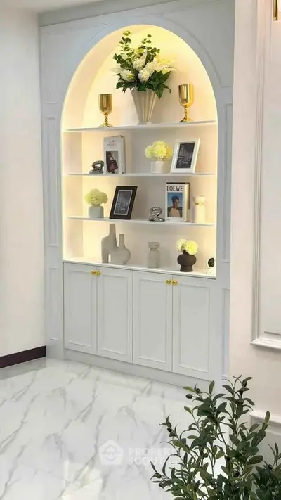 Elegant built-in white shelving unit with decorative items and soft lighting in a modern living space.
