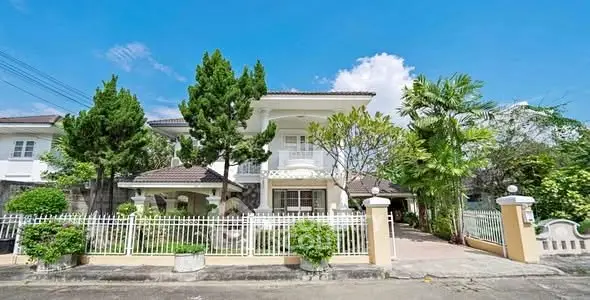 Charming two-story house with lush garden and white picket fence under a clear blue sky.