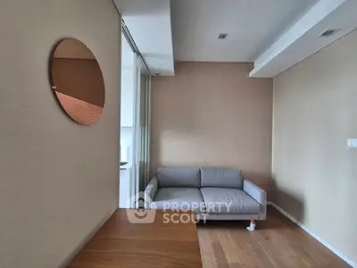 Modern living room with stylish sofa and wall mirror, featuring sleek wooden flooring.