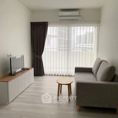 Modern living room with sleek furniture and large window offering natural light.