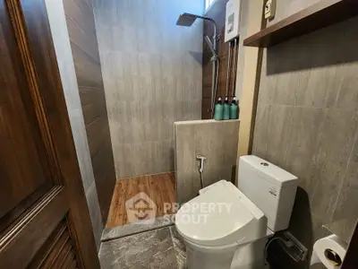 Modern bathroom with sleek shower and toilet, featuring elegant wood and tile design.