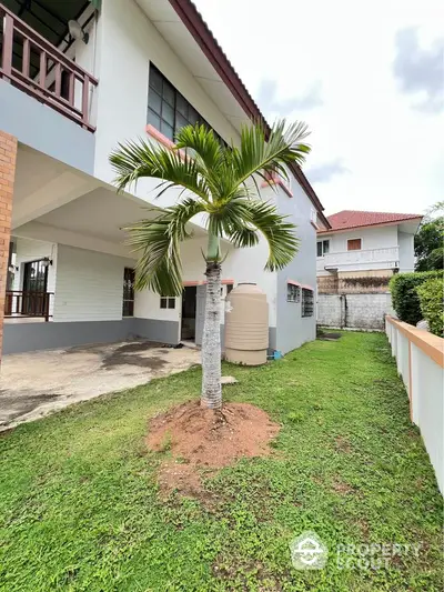 Charming suburban home with lush green lawn and palm tree, perfect for family living.