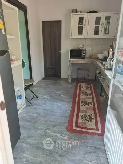 Charming kitchen with open layout and modern appliances, featuring a cozy rug and ample storage space.