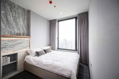 Modern bedroom with city view, featuring sleek design and large window for natural light.