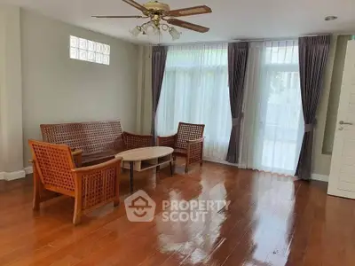 Spacious living room with wooden furniture and large windows for natural light.