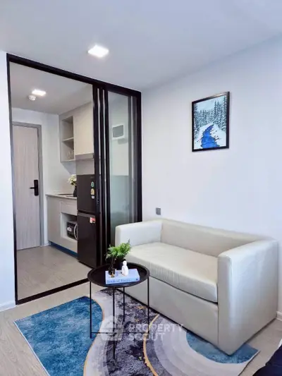 Modern living room with sleek design and compact kitchen area, featuring a cozy sofa and stylish decor.