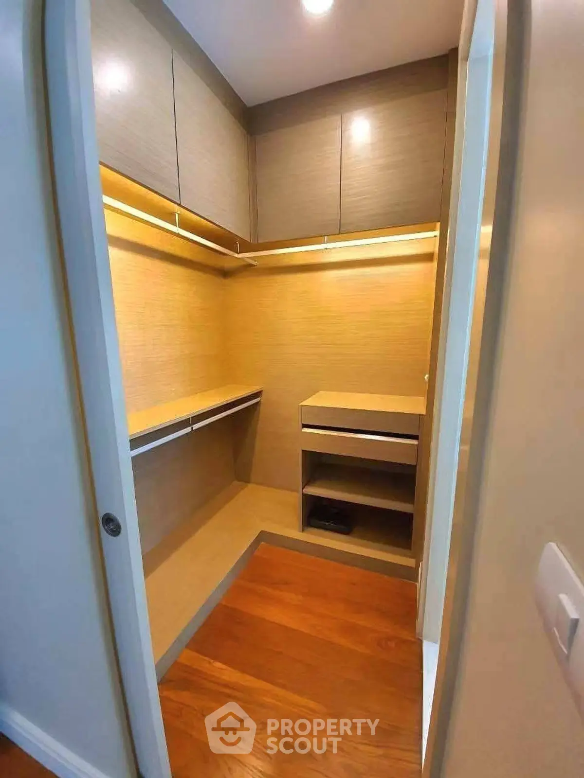 Spacious walk-in closet with wooden flooring and ample storage space.