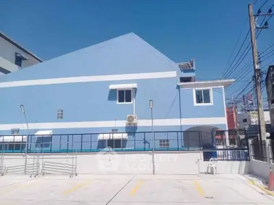 Charming blue building exterior with spacious parking area under clear skies.